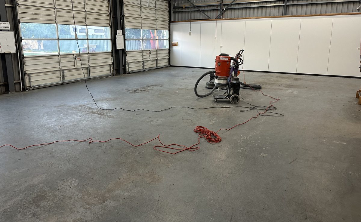 Bare concrete warehouse floor before, during grinding prep